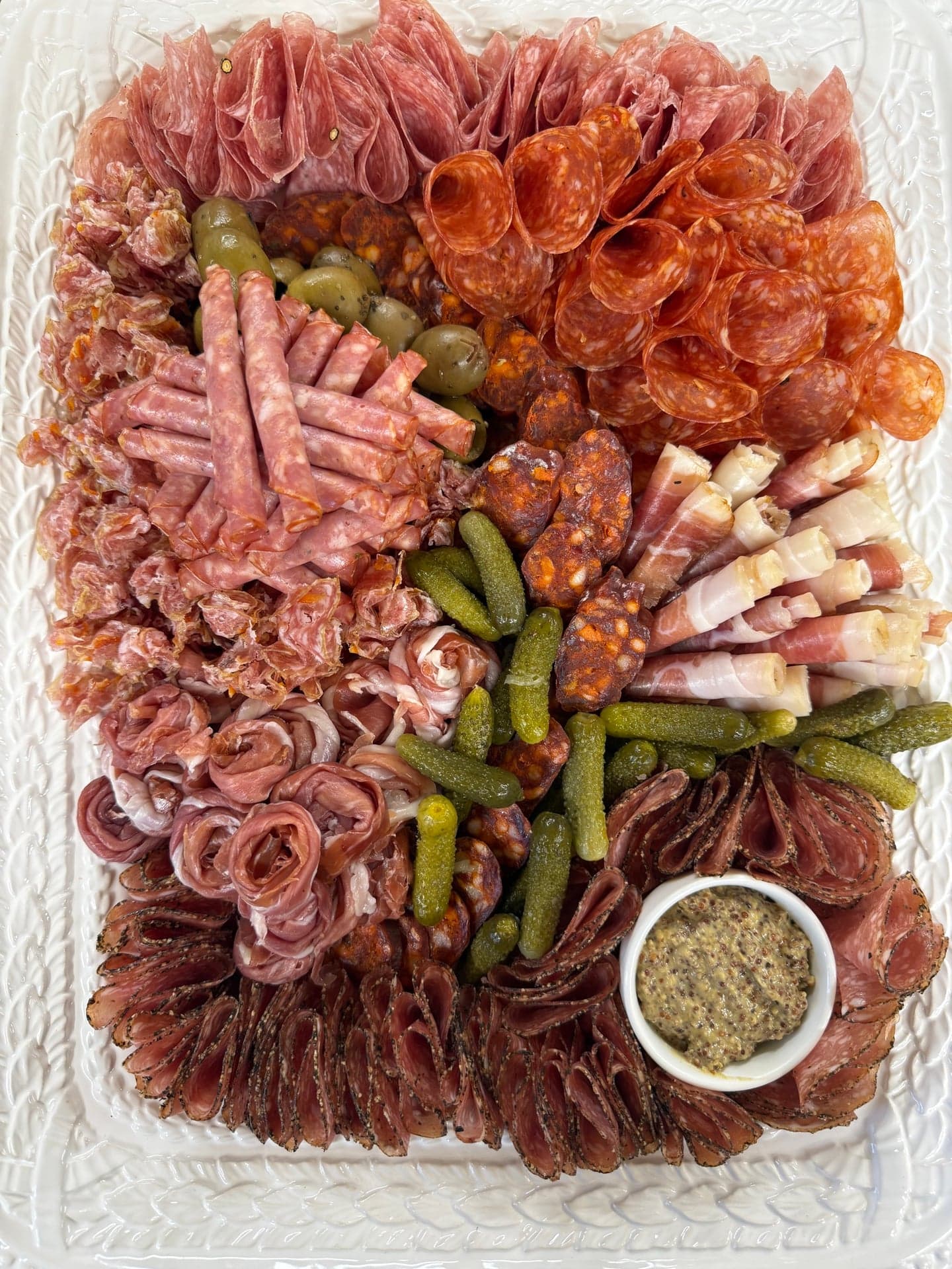 A charcuterie board built at Ottavio — soppressata, prosciutto, salami, cornichons, olives and grainy mustard
