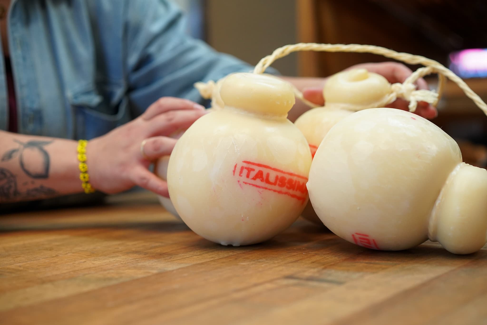 Pear-shaped provolone being tied by hand at the counter